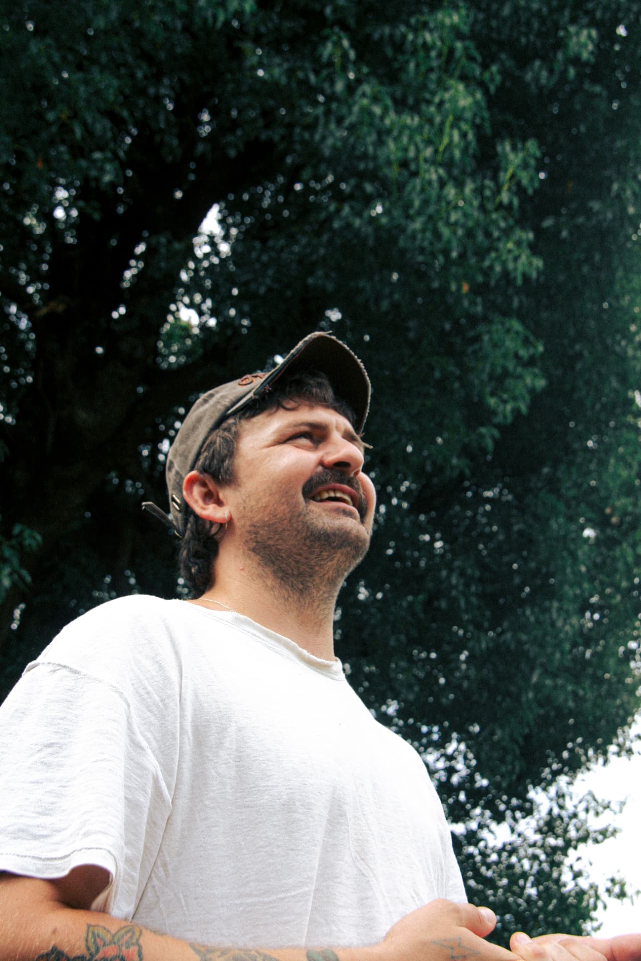 Adam Newling outdoors beneath trees, photographed from a low angle